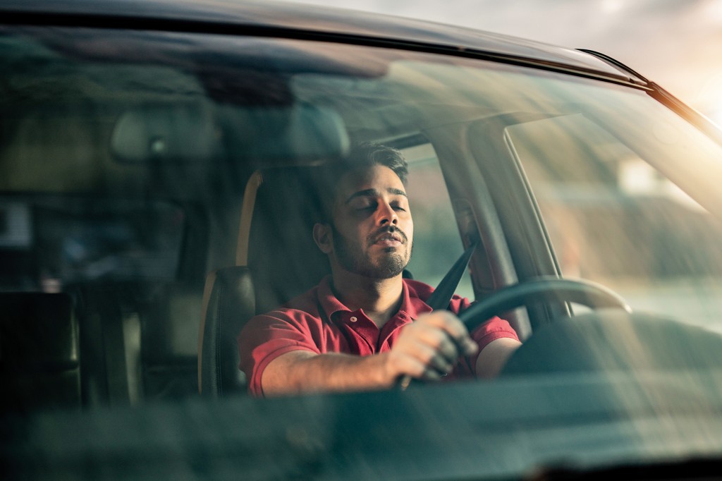 Middle Eastern man falling a sleep while driving a car.